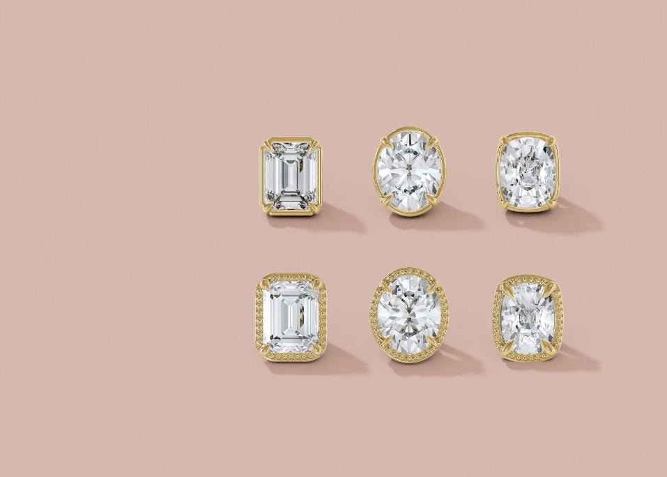 Six diamond stud earrings in gold bezel settings on blush background
